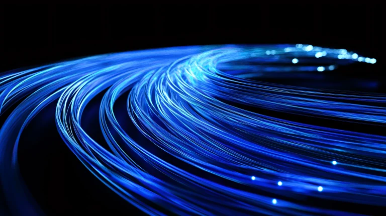 Abstract image of numerous bright blue, glowing light strands curving in a stream against a black background, representing high-speed data flow and fiber optic cables.